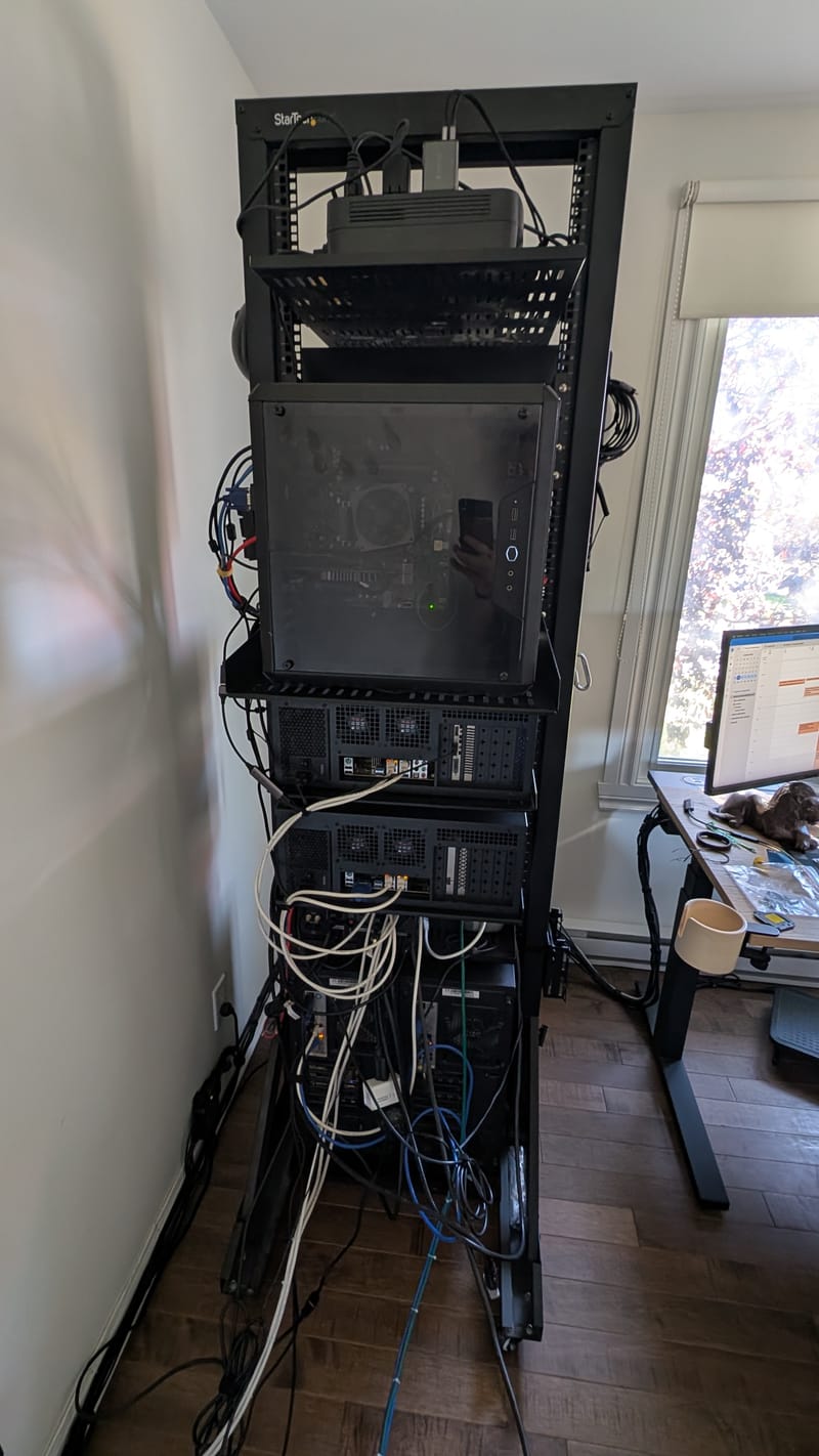 Le rack vu de côté, près de la fenêtre : un boîtier en haut, les deux Rosewill en dessous, et le câblage réseau et USB qui descend vers la switch